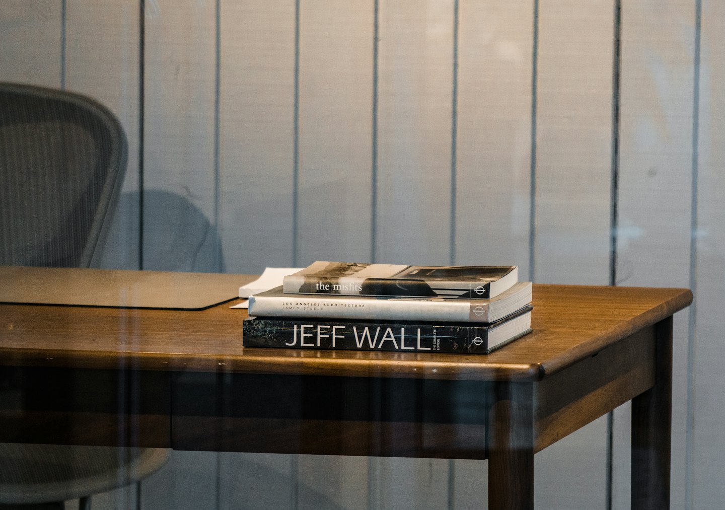 Three stacked art books resting on a polished wooden desk.